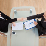 Women shaking hands over a desk