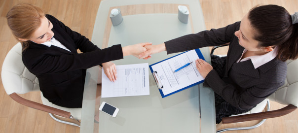 Women shaking hands over a desk